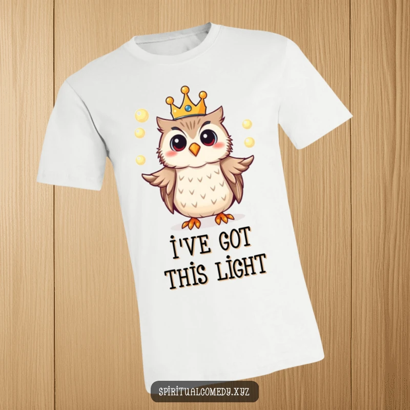 Funny t-shirt depicting a cheerful owl wearing a tiny crown, juggling luminous orbs of light with enchanting grace.